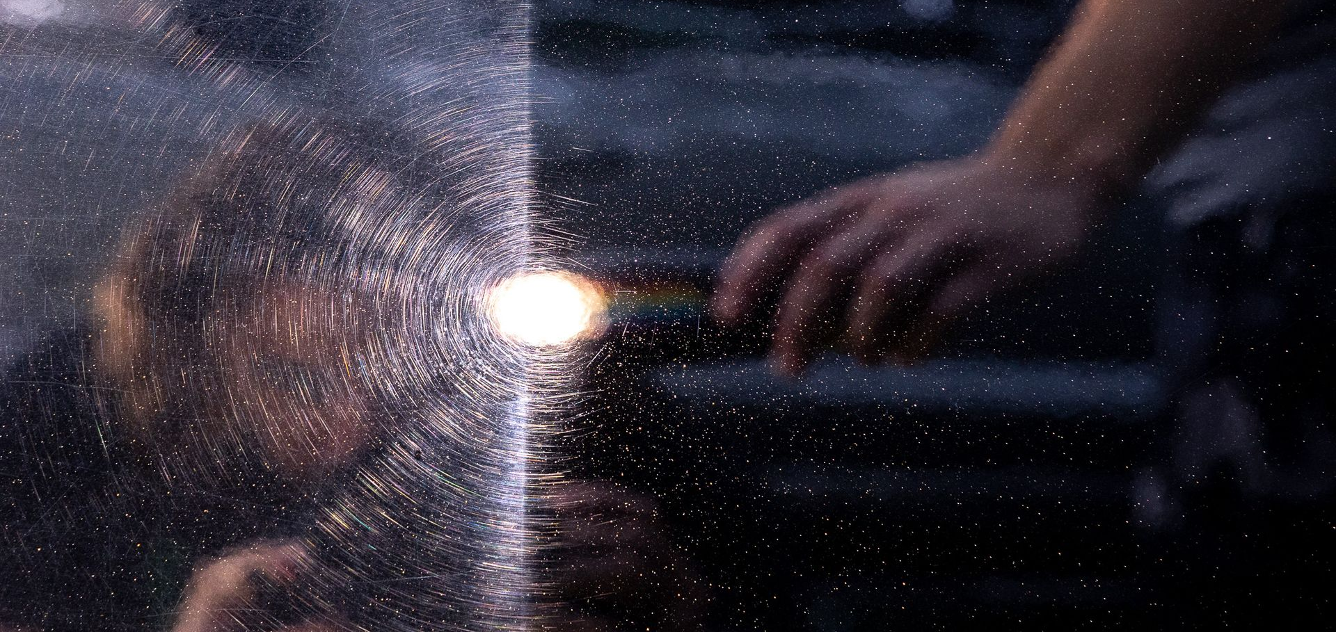Light reflecting off of a black vehicle's paint, revealing extreme car wash swirls on one side and a polished finish on the other side. 