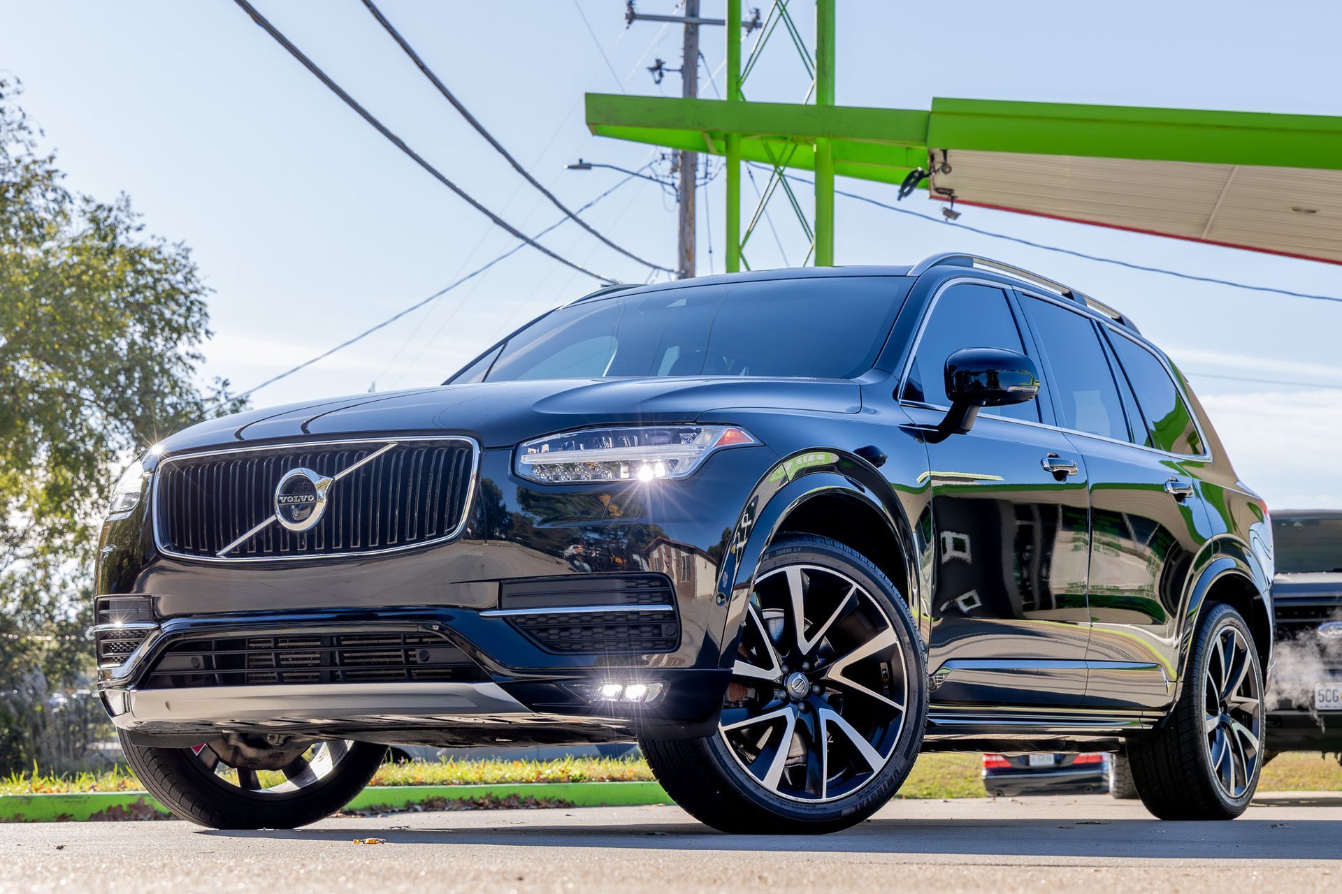 Black Volvo SUV with custom black and silver wheels, parked on a street.