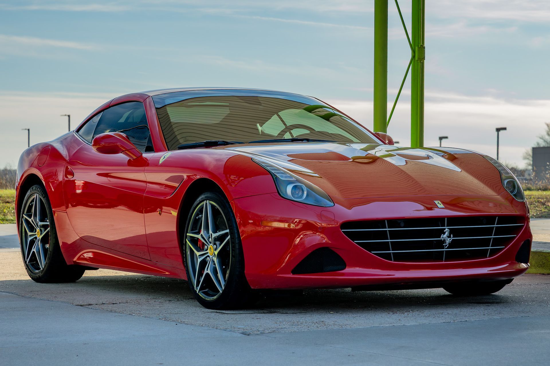 Red Ferrari California parked outside on a sunny day.