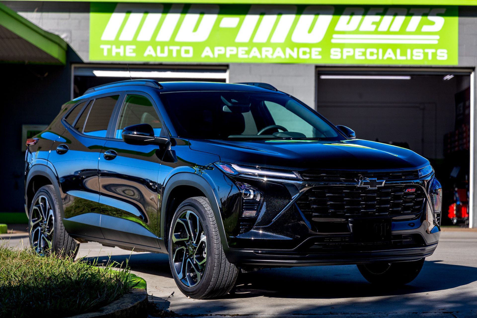 A black car is parked in front of a building that says the auto appearance specialists
