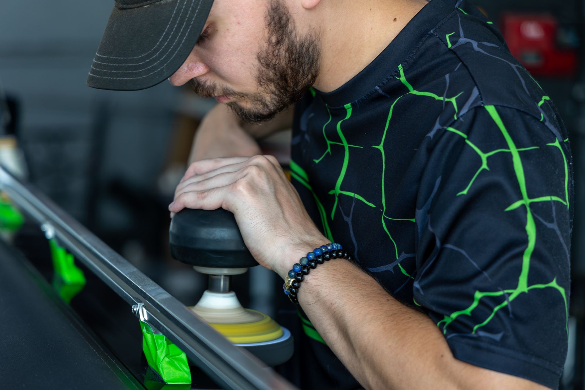 A man is polishing a car windshield with a machine.