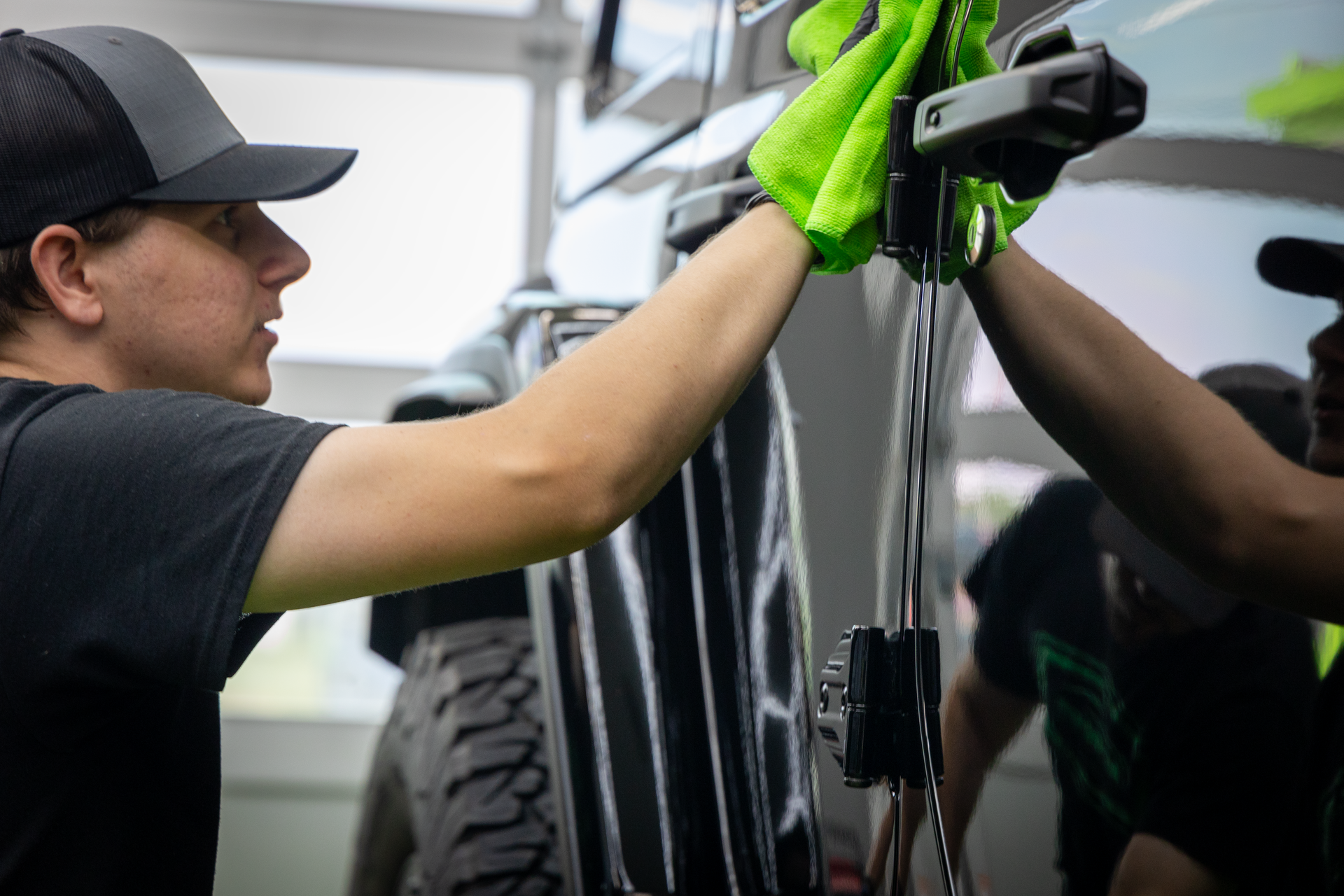 A man is cleaning a car with a towel.
