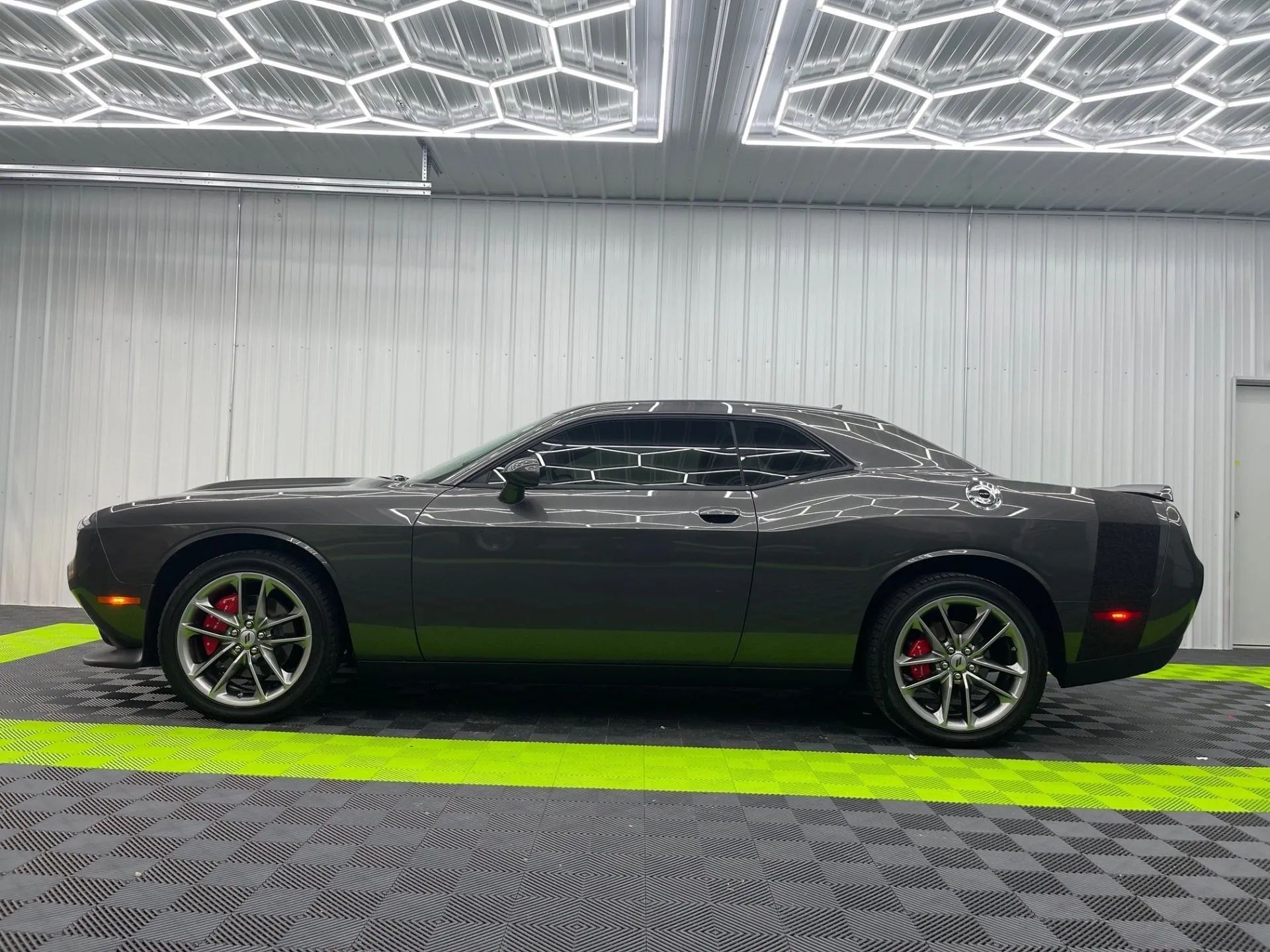 A black dodge challenger is parked in a garage.