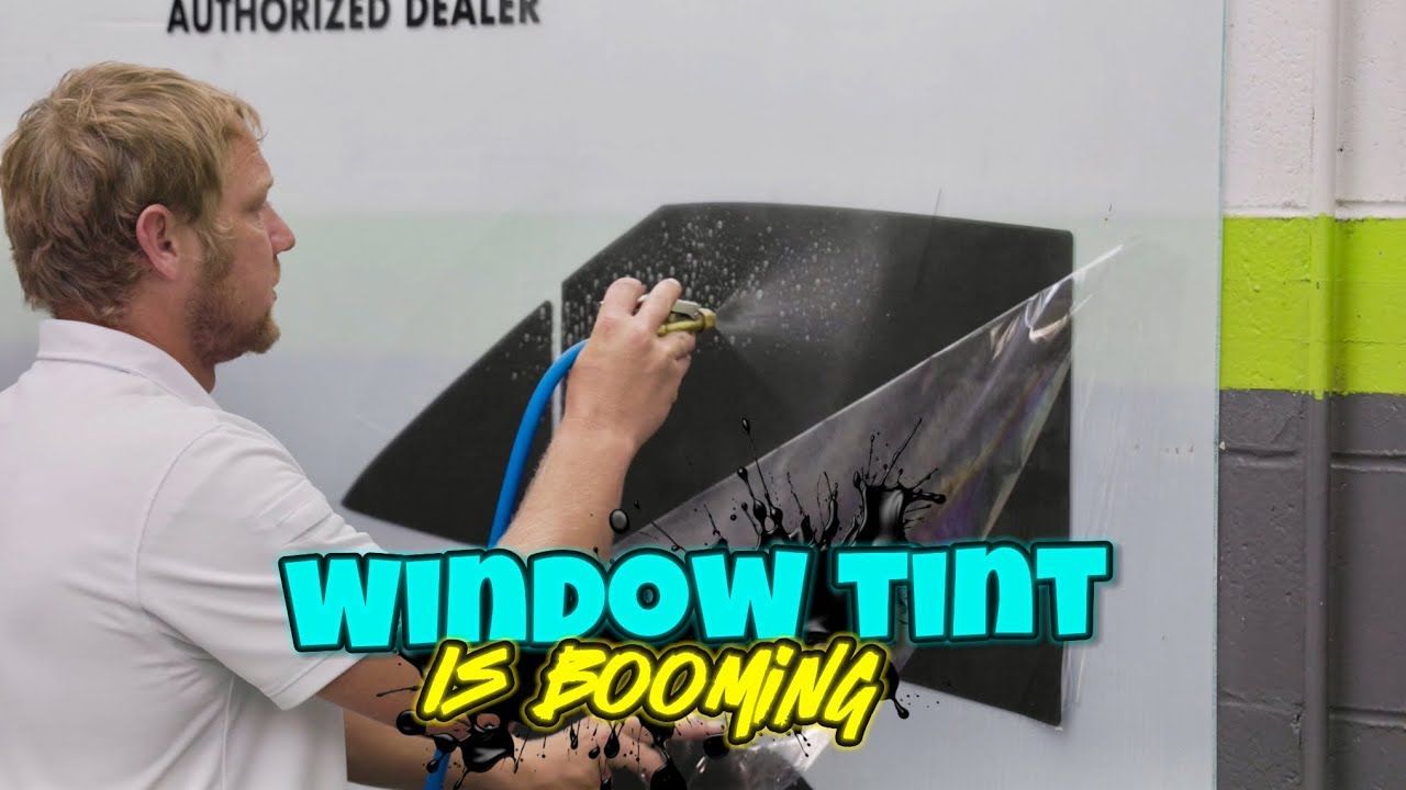 A man is applying window tint to a car window.