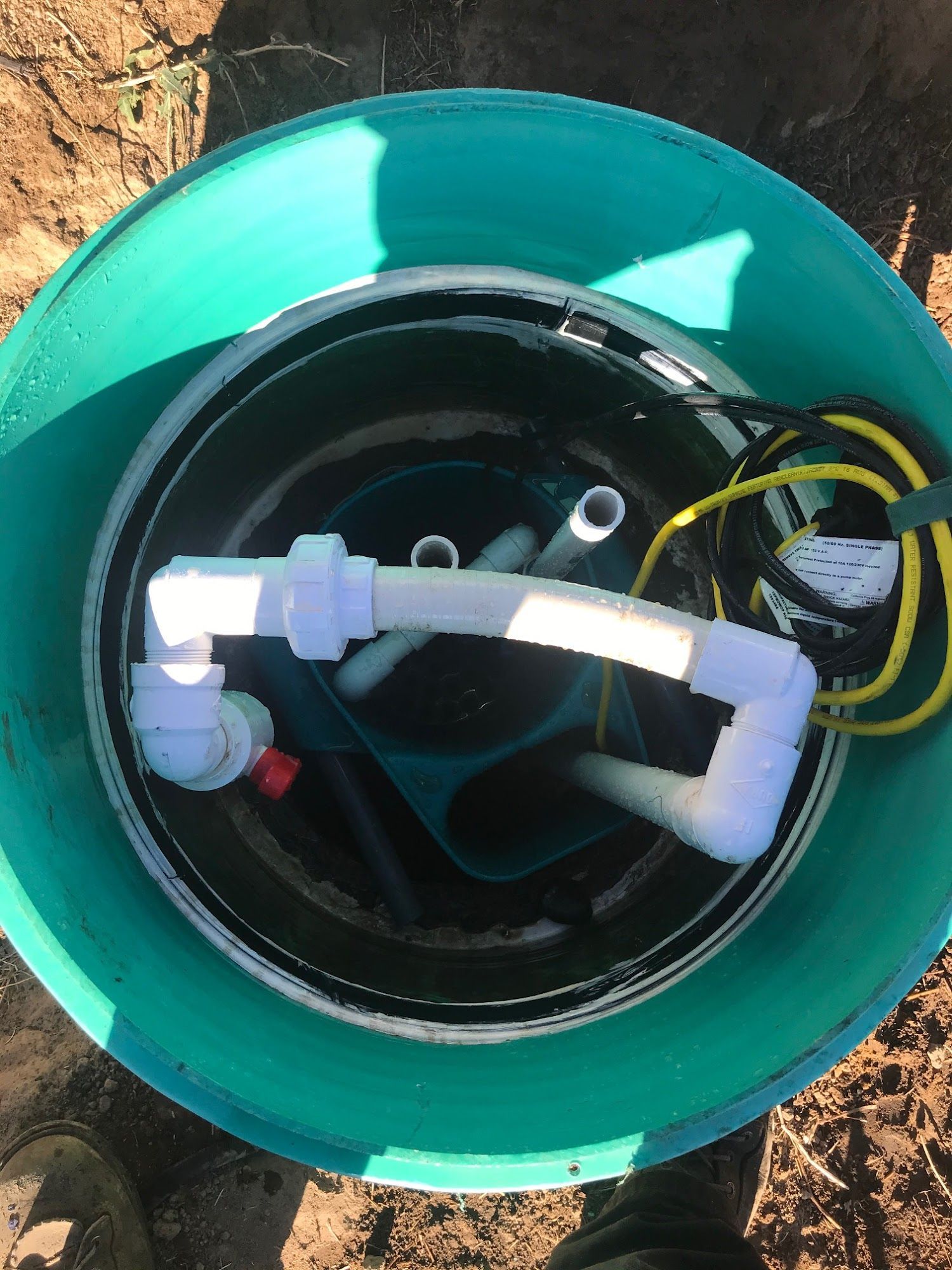 Overhead view of a green plastic container holding plumbing and electrical components,