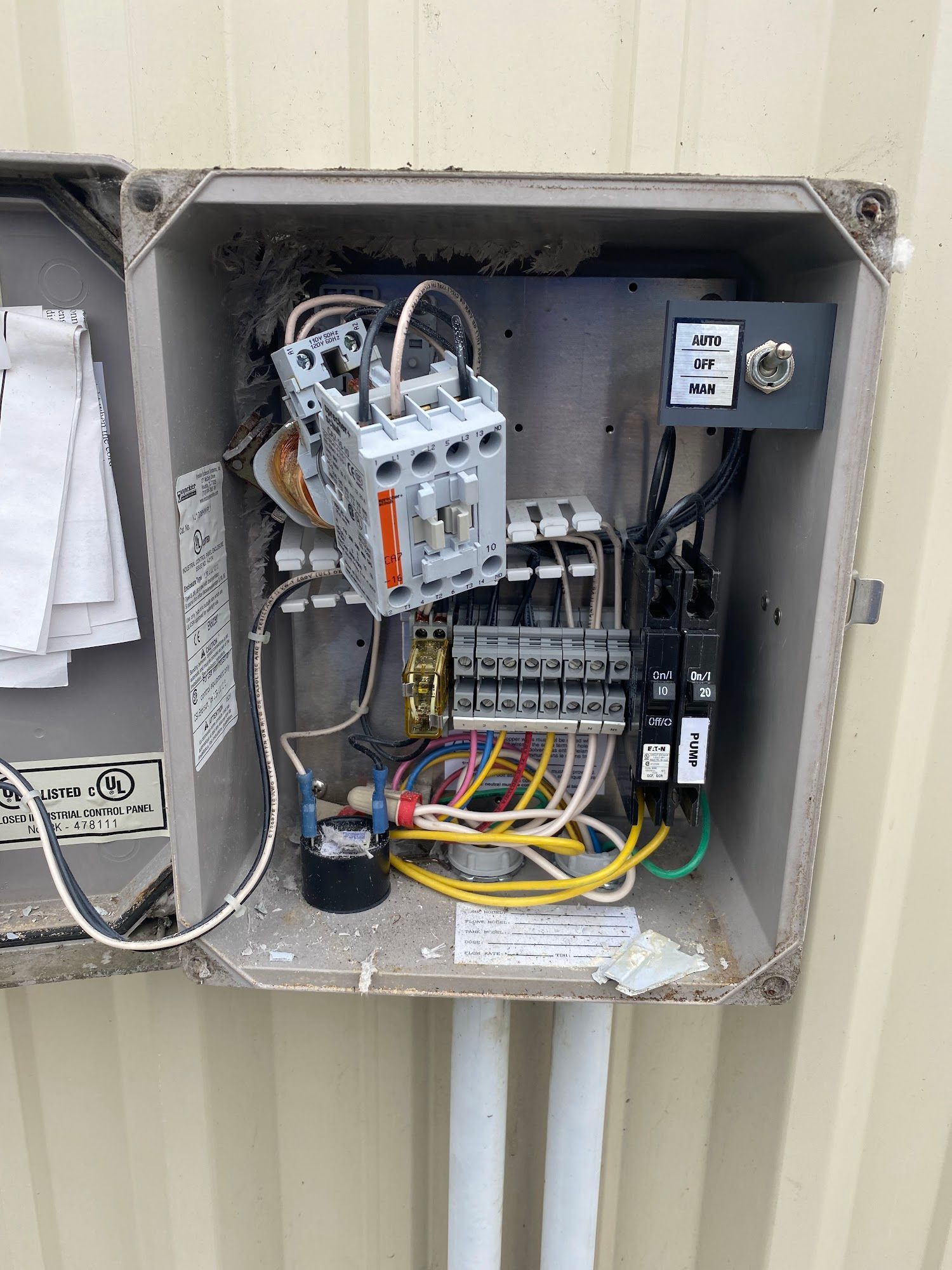 Open electrical control box with wiring, circuit breakers, and a large contactor, mounted on a wall.