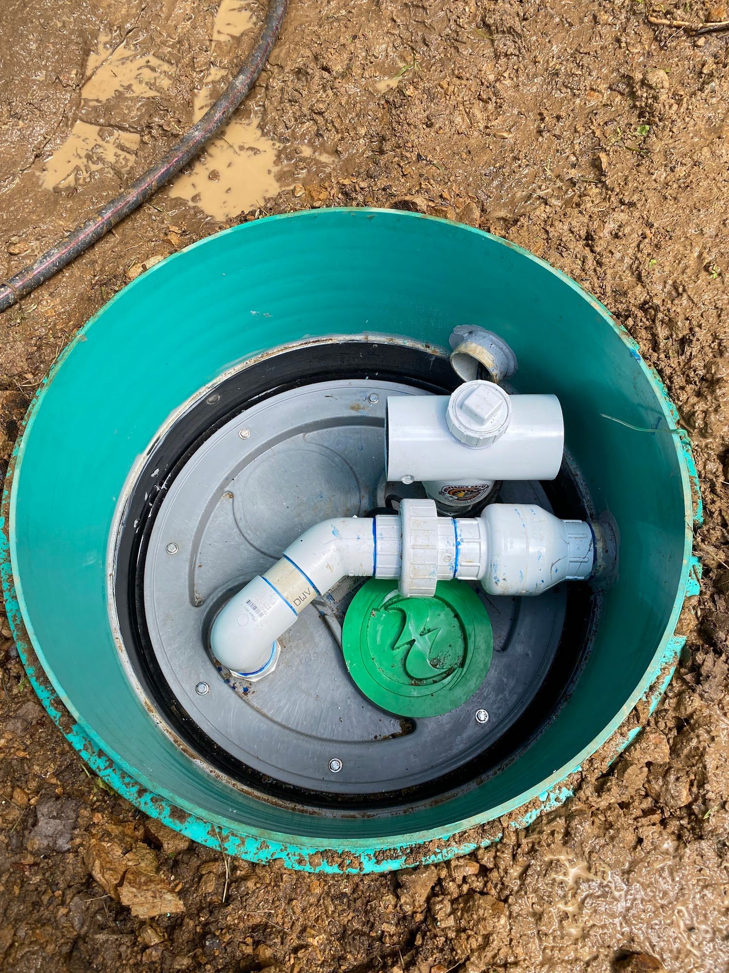 Green septic tank access point with pipes, in dirt.