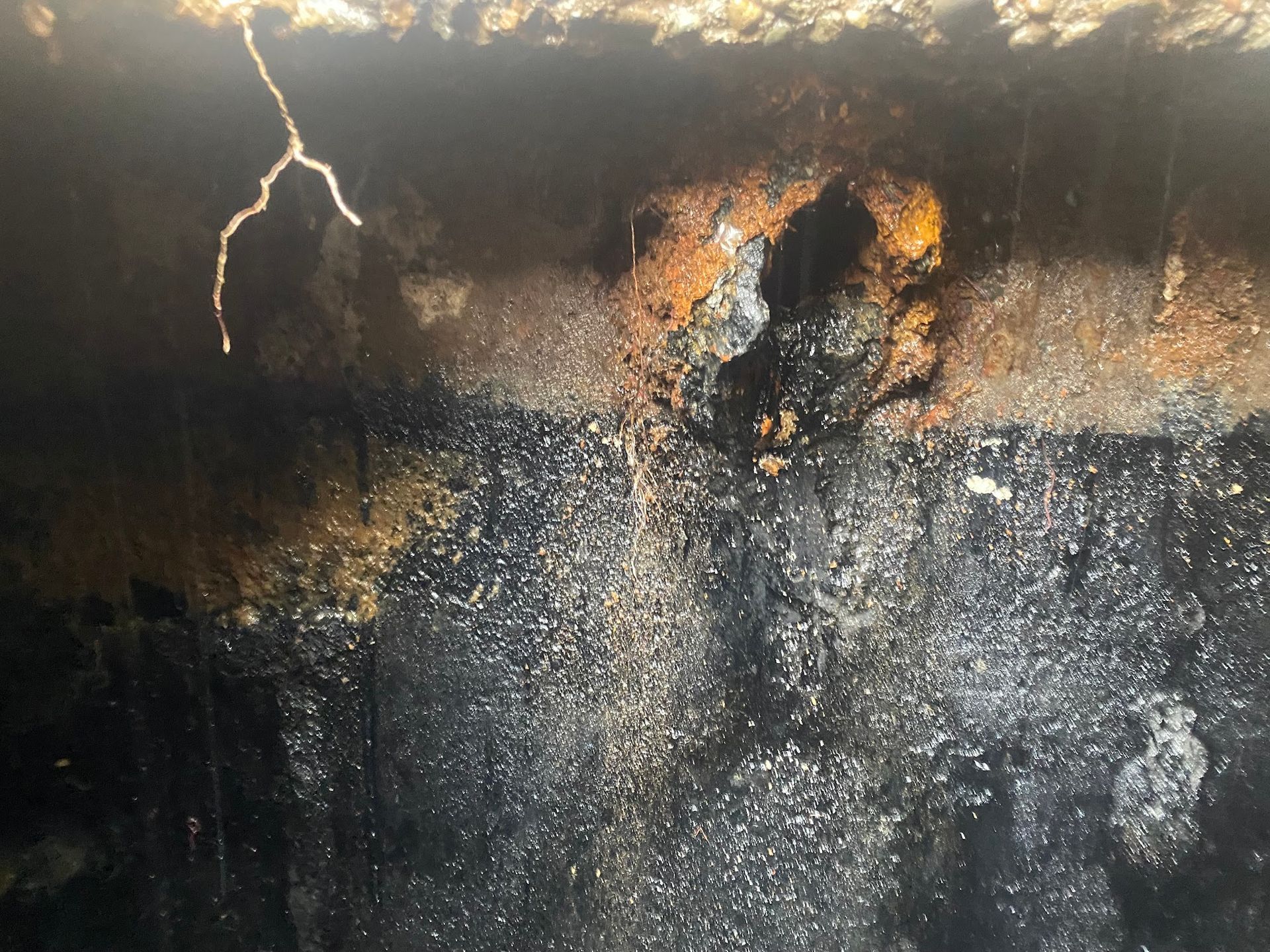 Corroded metal surface with rust and dark streaks, possibly a damaged tank.