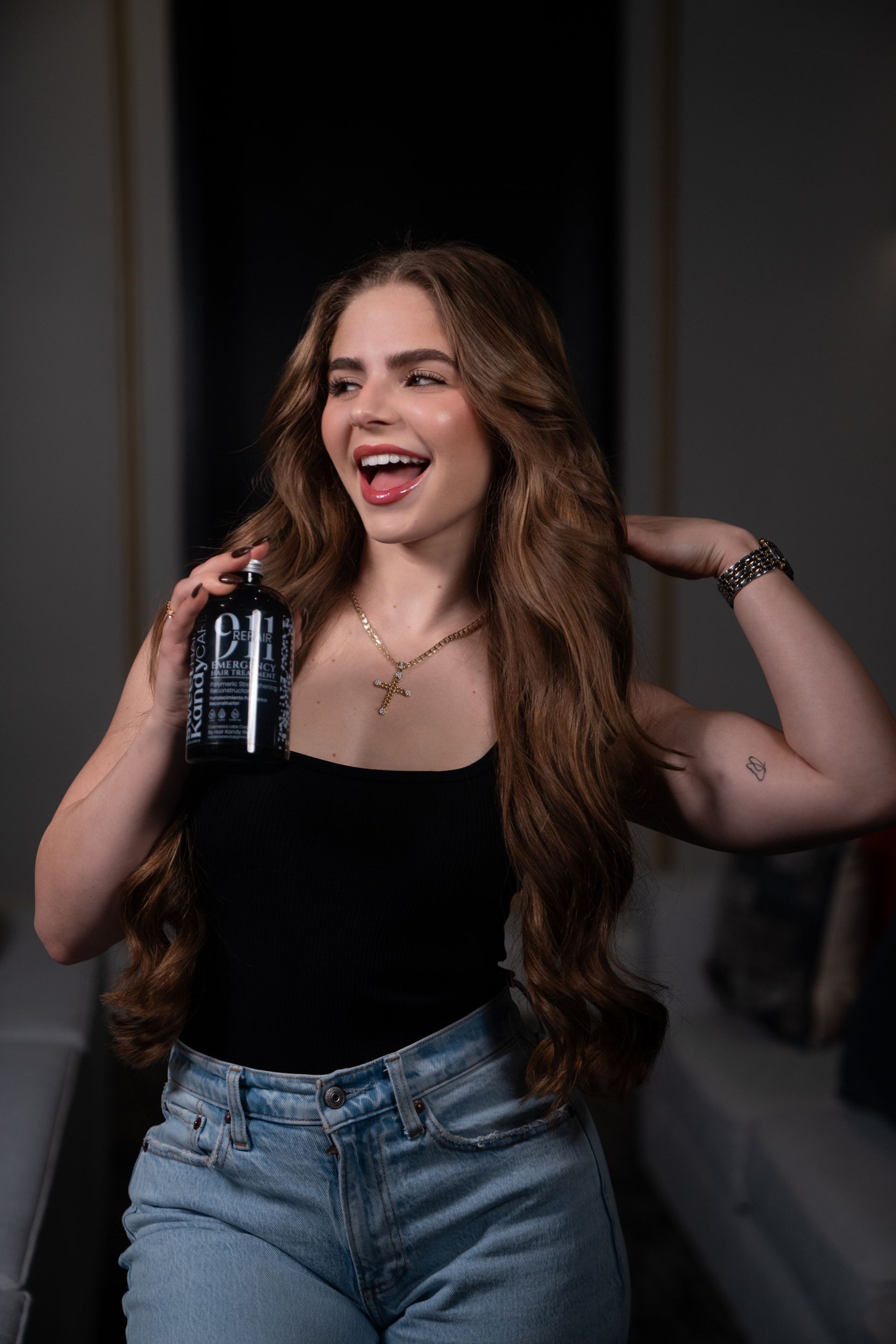 A woman with long hair is holding a bottle of shampoo in her hand.