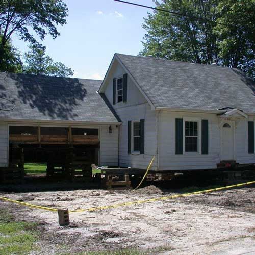 A white house with black shutters is being moved