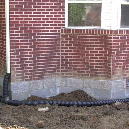 A brick building with a drain pipe coming out of it.