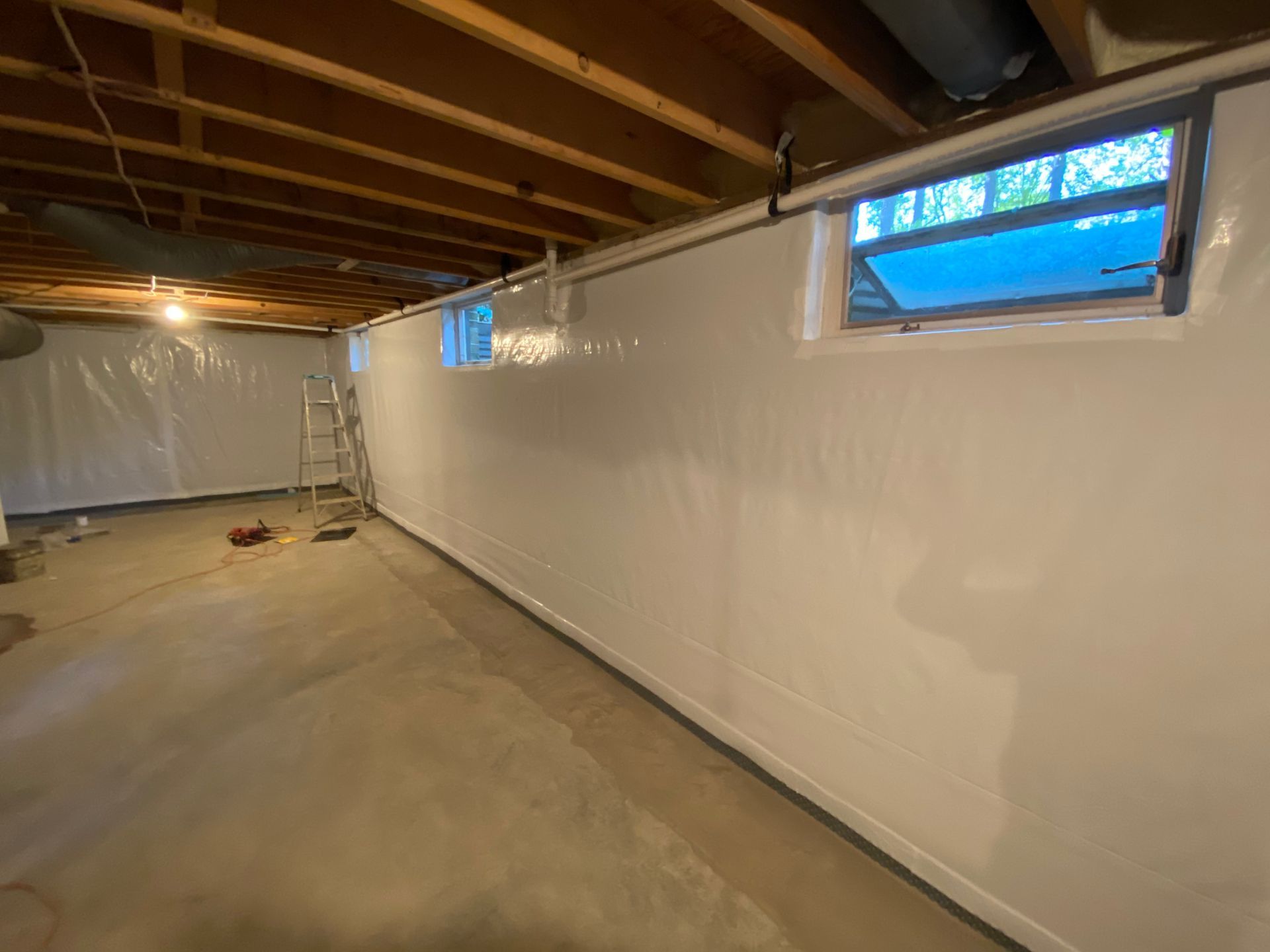 A basement with a white wall and a window where leaks have been fixed.