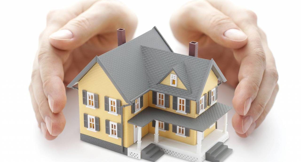 A person is holding a model house in their hands.