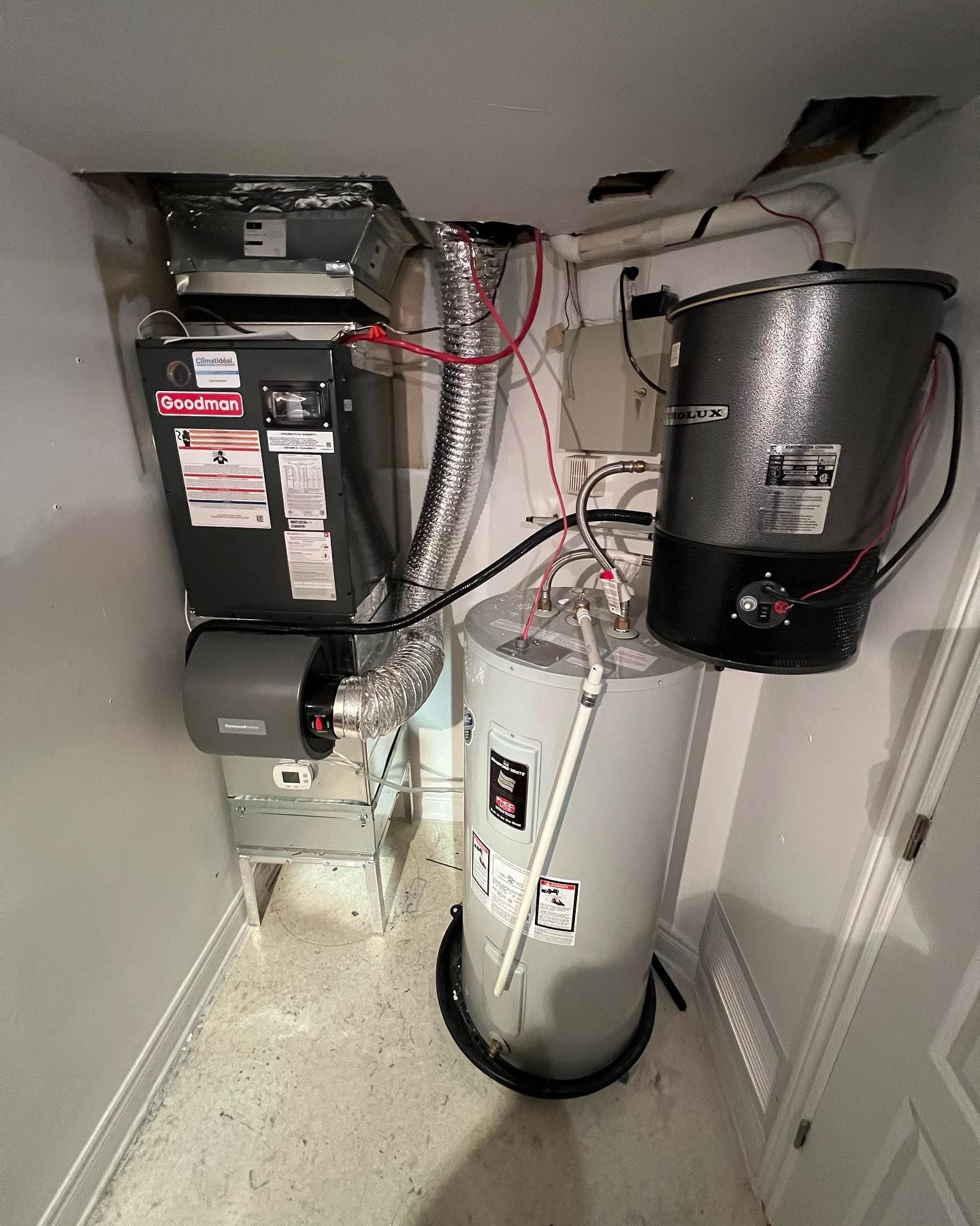 A room with a water heater , air conditioner , and vacuum cleaner.