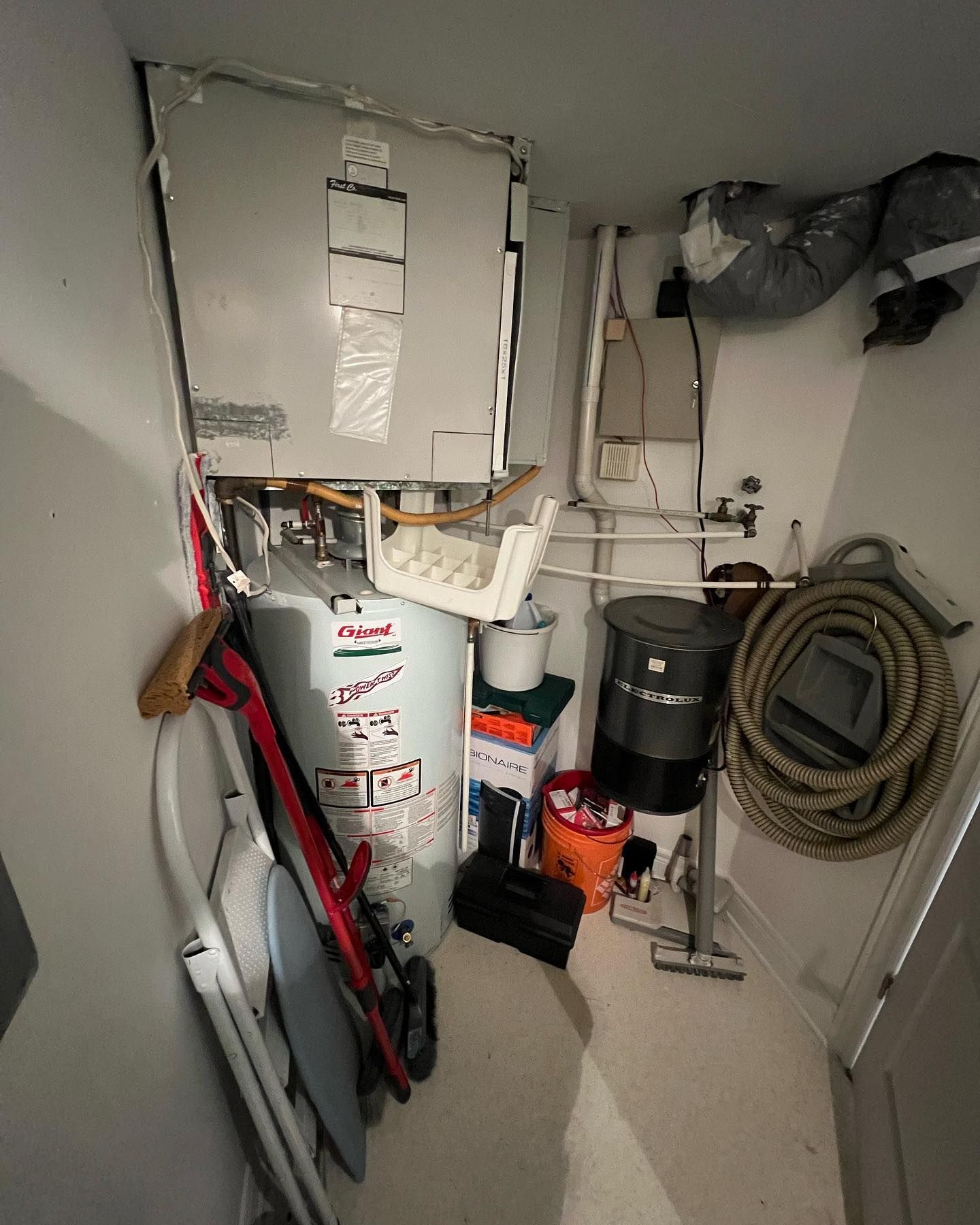 A room with a water heater and a vacuum cleaner.