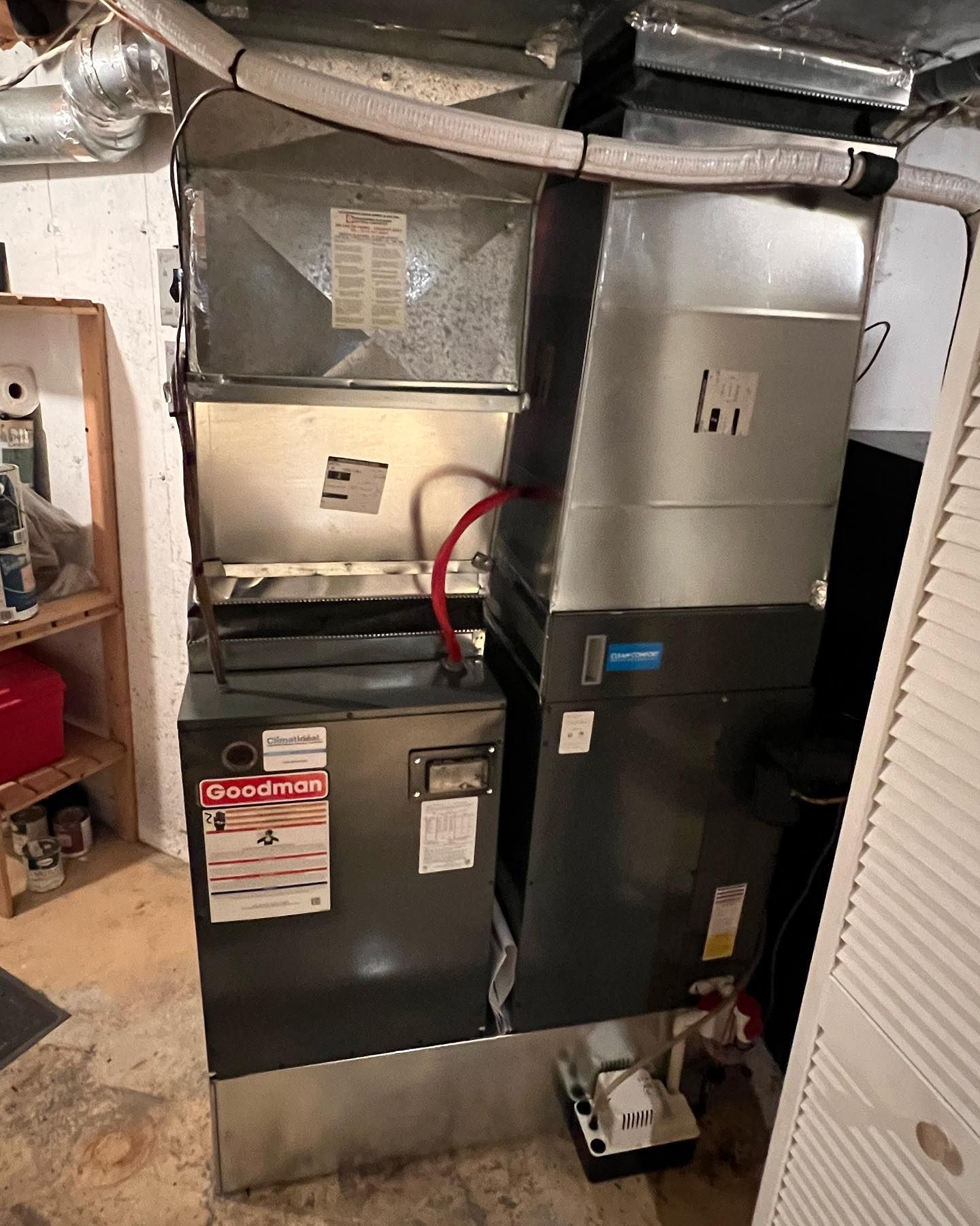 Two air conditioners are sitting next to each other in a basement.