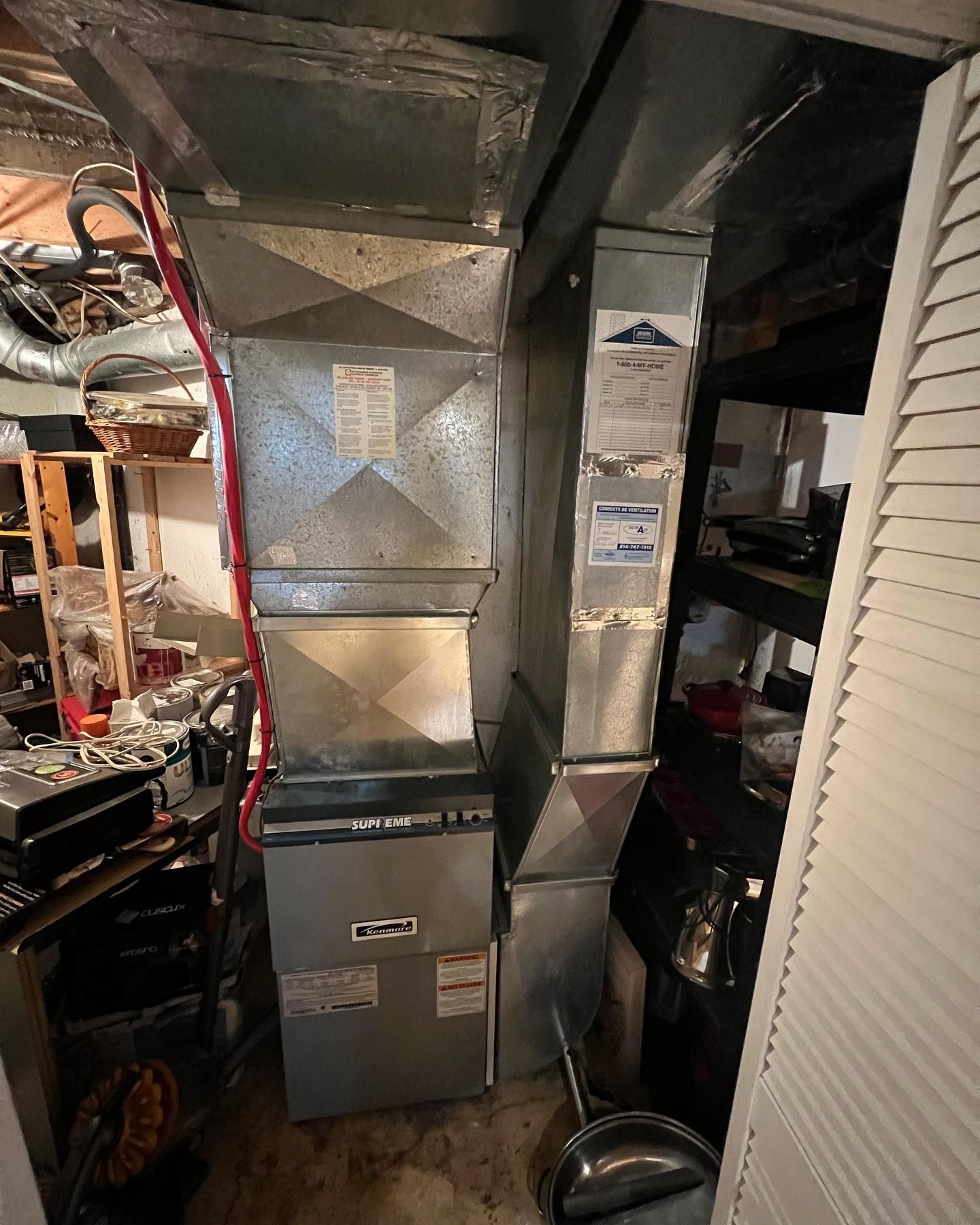 An air conditioner is sitting in a closet next to a ladder.