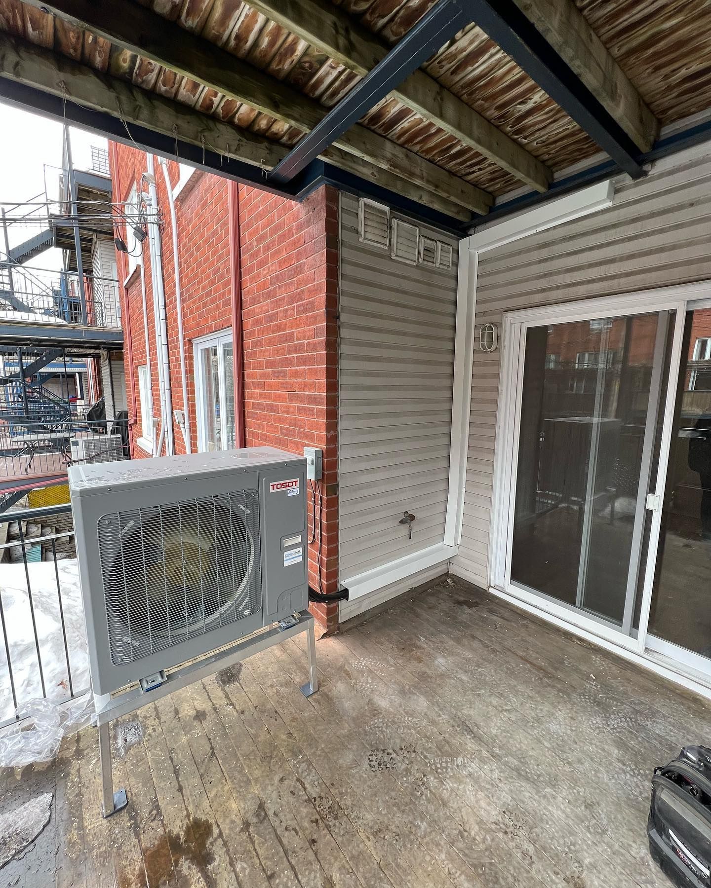 A patio with a sliding glass door and a large air conditioner hanging from the ceiling.