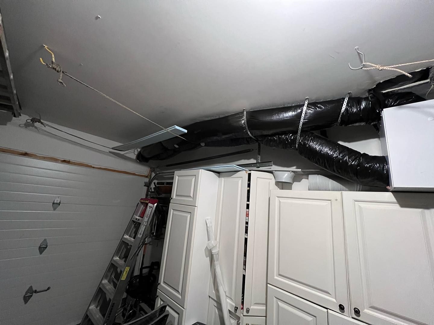 A black pipe is hanging from the ceiling of a garage.
