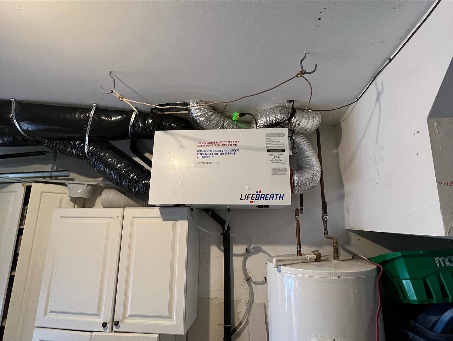 A kitchen with white cabinets and a water heater