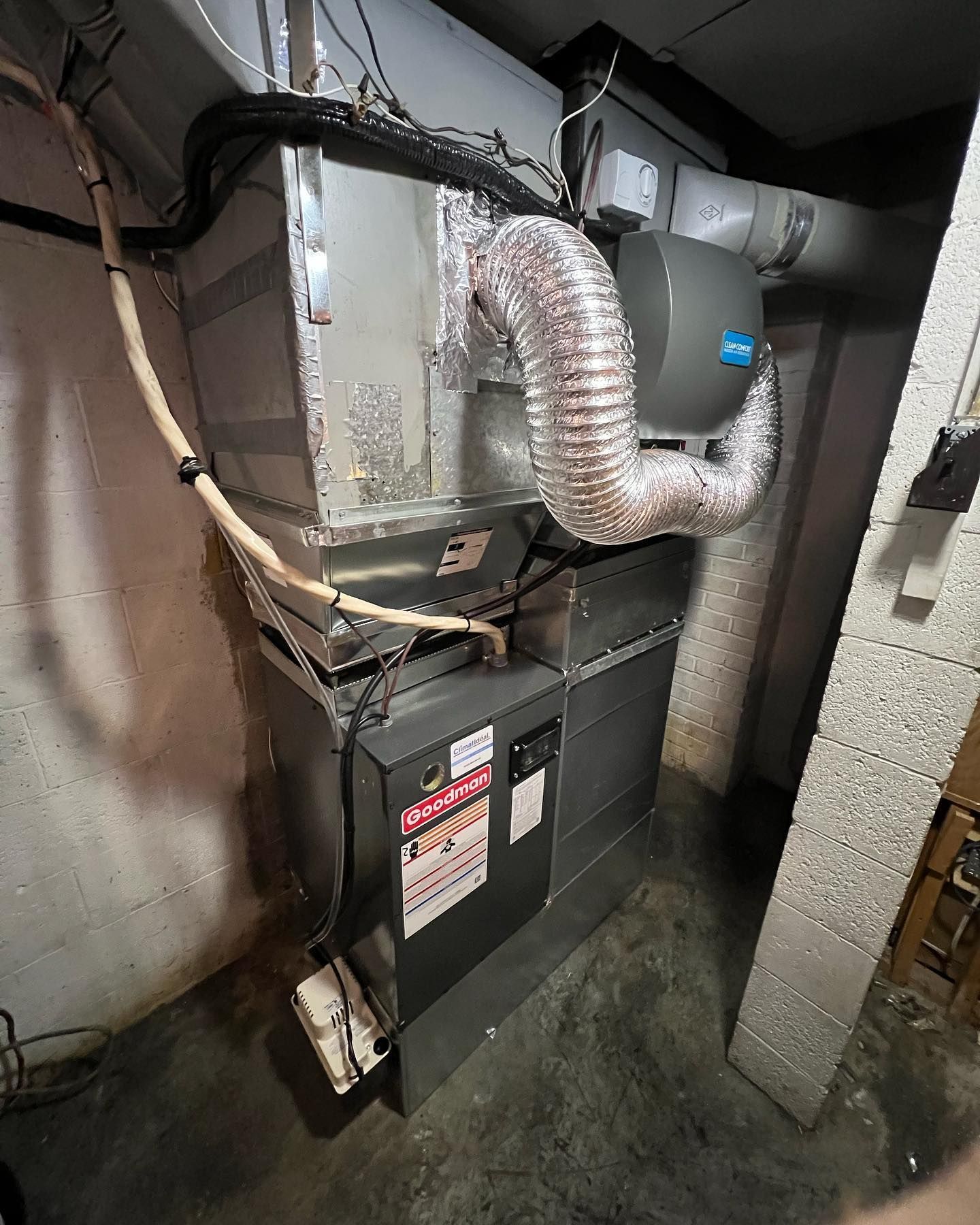 An air conditioner is sitting in a basement next to a wall.