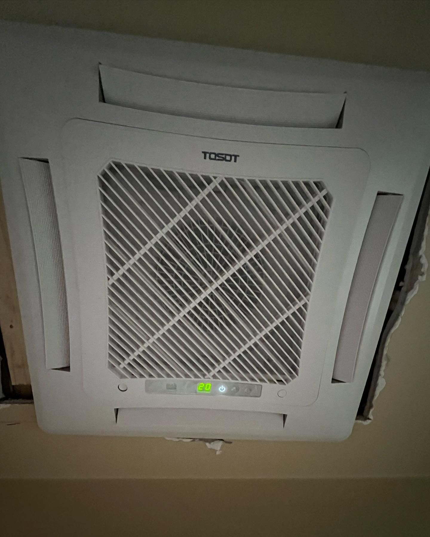 A white air conditioner is hanging from the ceiling in a room.