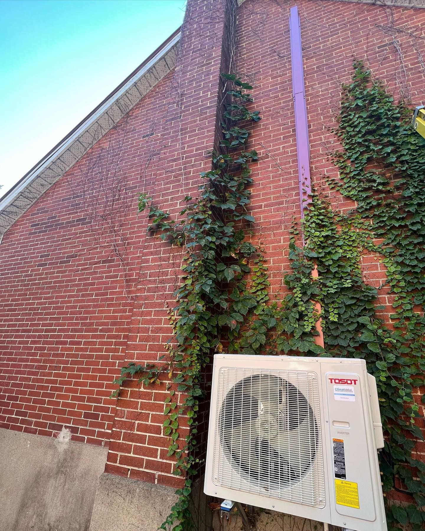 A white air conditioner is sitting on the side of a brick building.