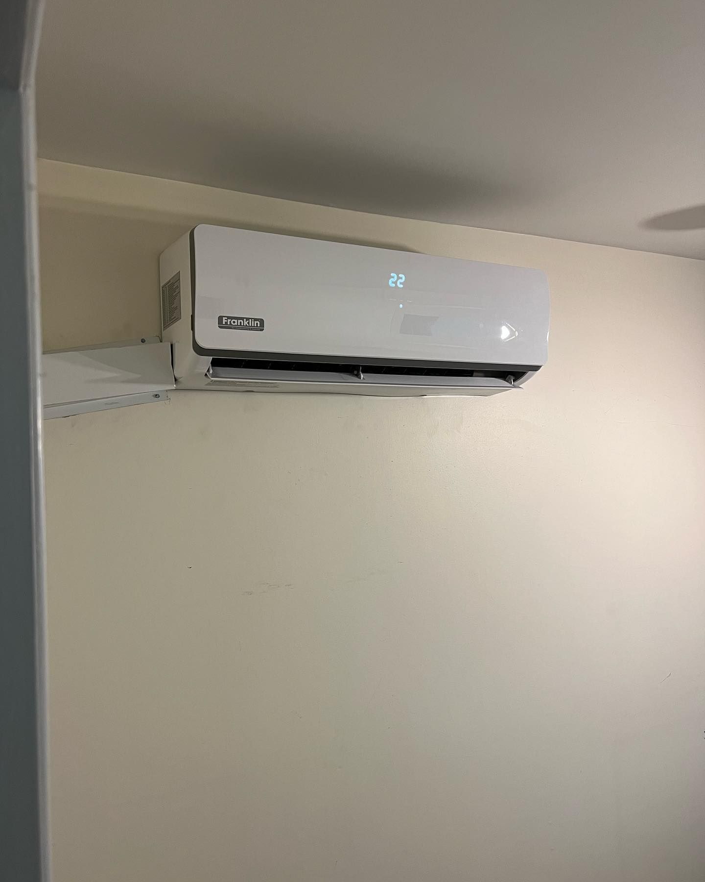 A white air conditioner is hanging from the ceiling in a room.