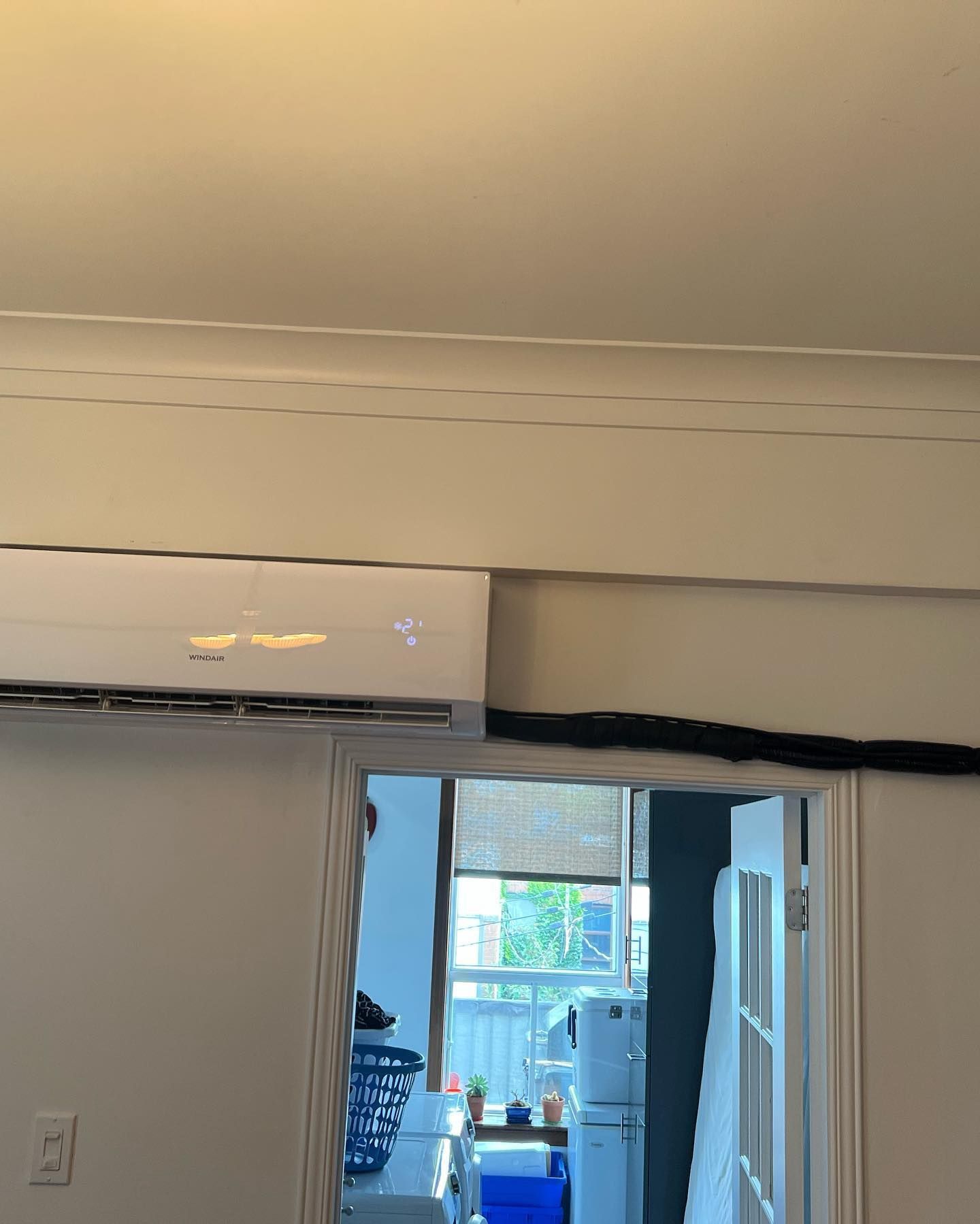 A white air conditioner is hanging from the ceiling in a room.