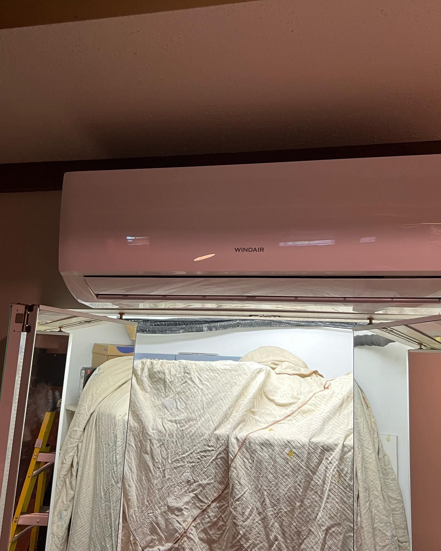 A pink air conditioner is hanging from the ceiling in a room.