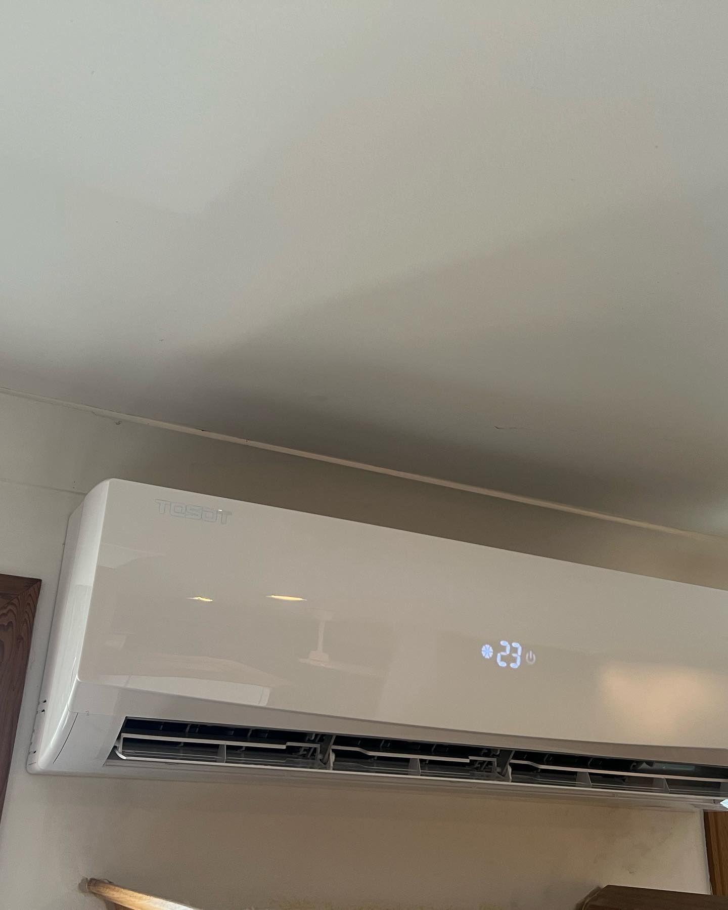 A white air conditioner is hanging from the ceiling in a room.