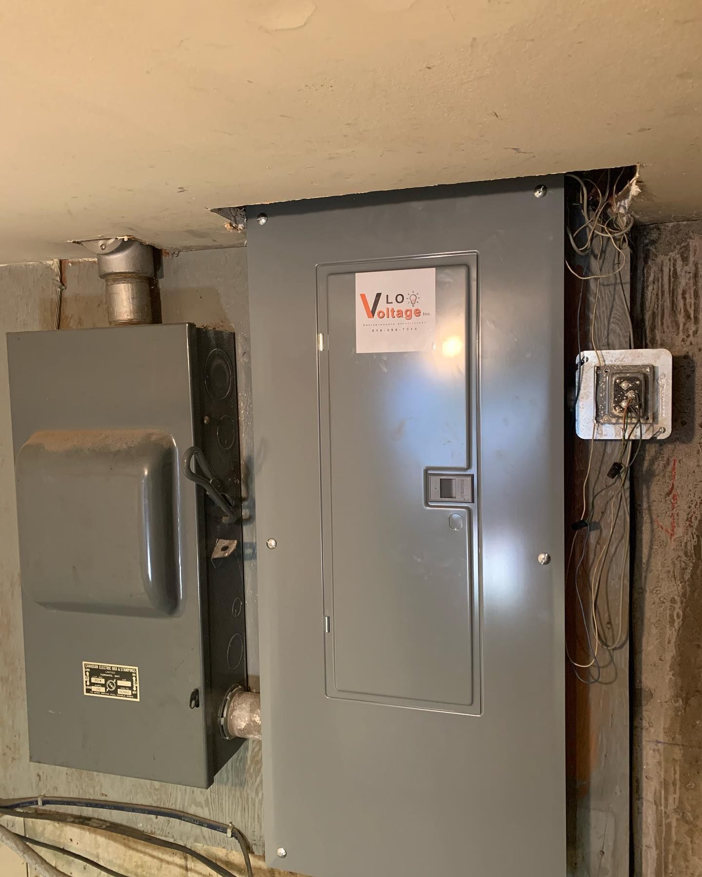 A gray electrical box is sitting on a wall next to a switch.