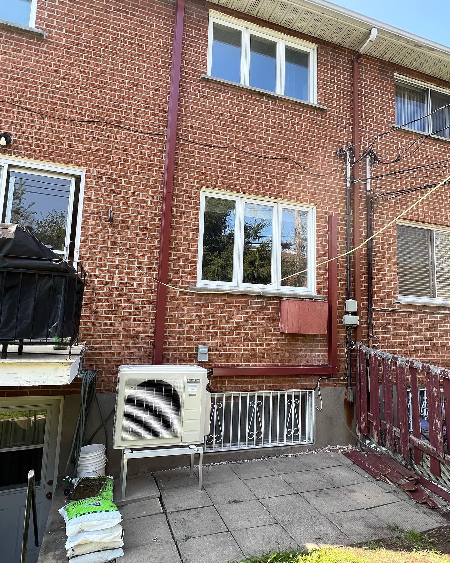 The back of a brick house with a large air conditioner on the side of it.