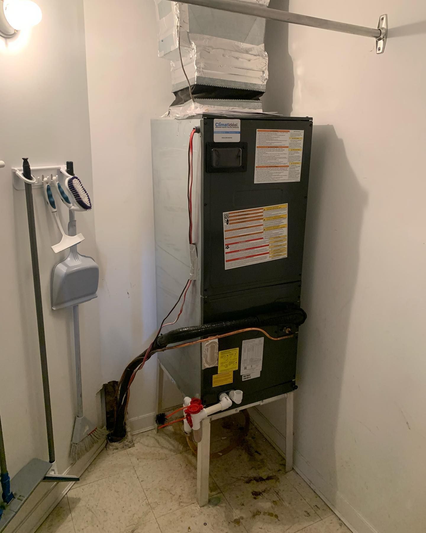 A room with a heater and a broom on the floor.