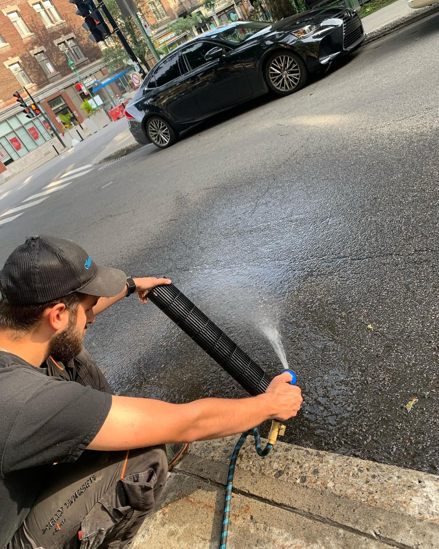 A man is spraying water on the side of the road.