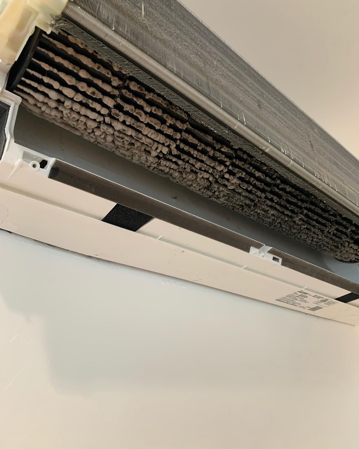 A close up of a dirty air conditioner hanging on a wall.