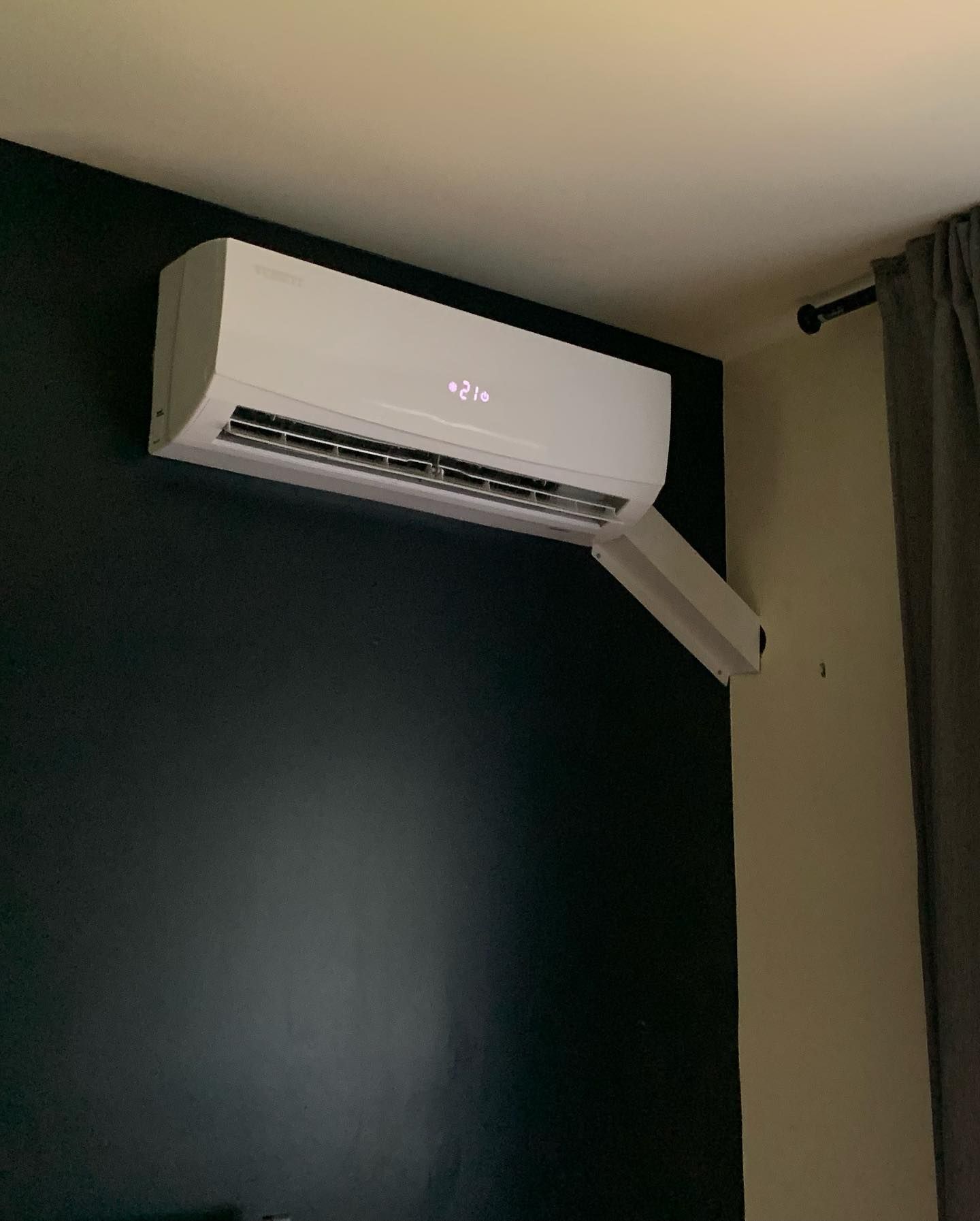 A white air conditioner is hanging from the ceiling in a room.