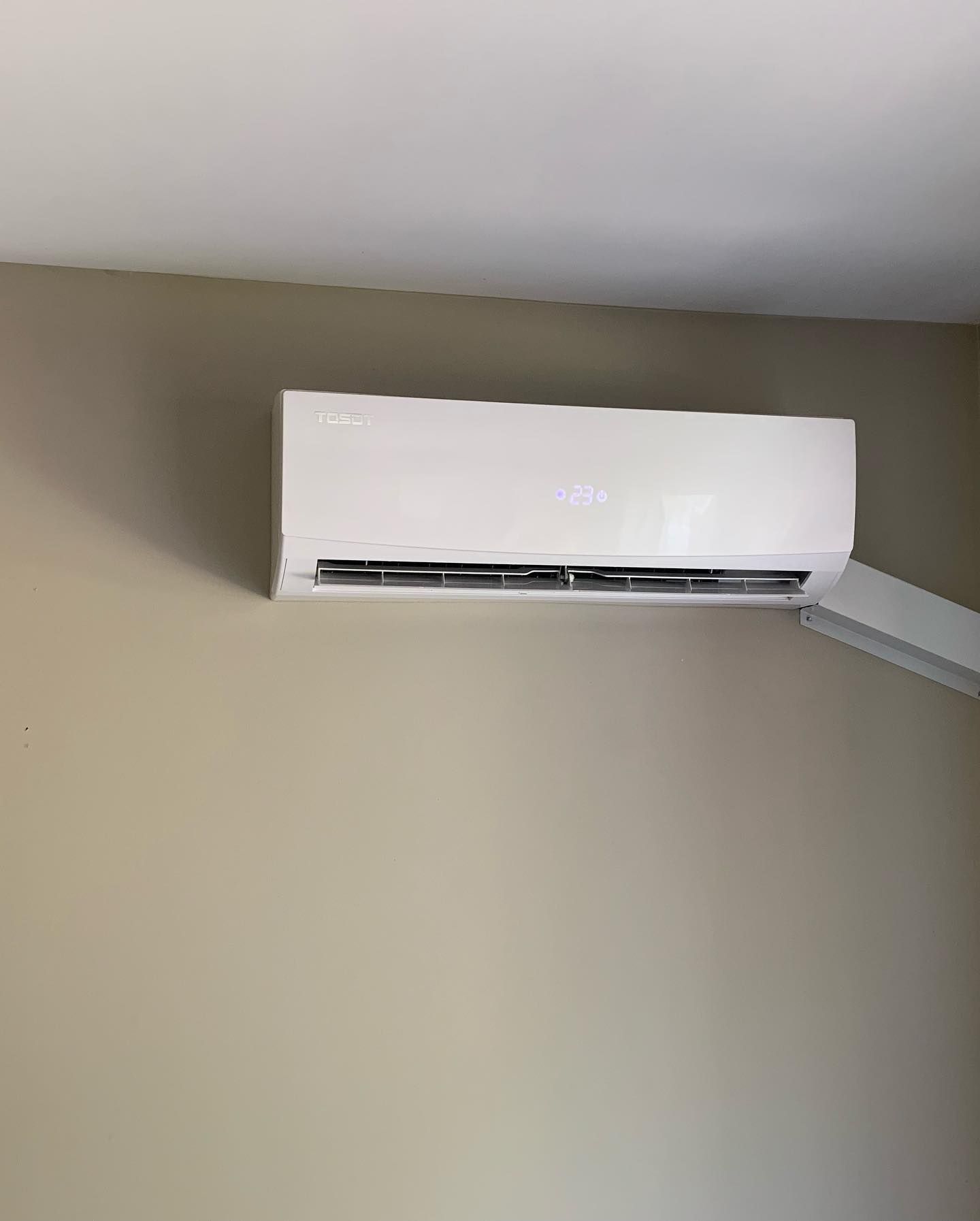 A white air conditioner is hanging on a wall in a room.