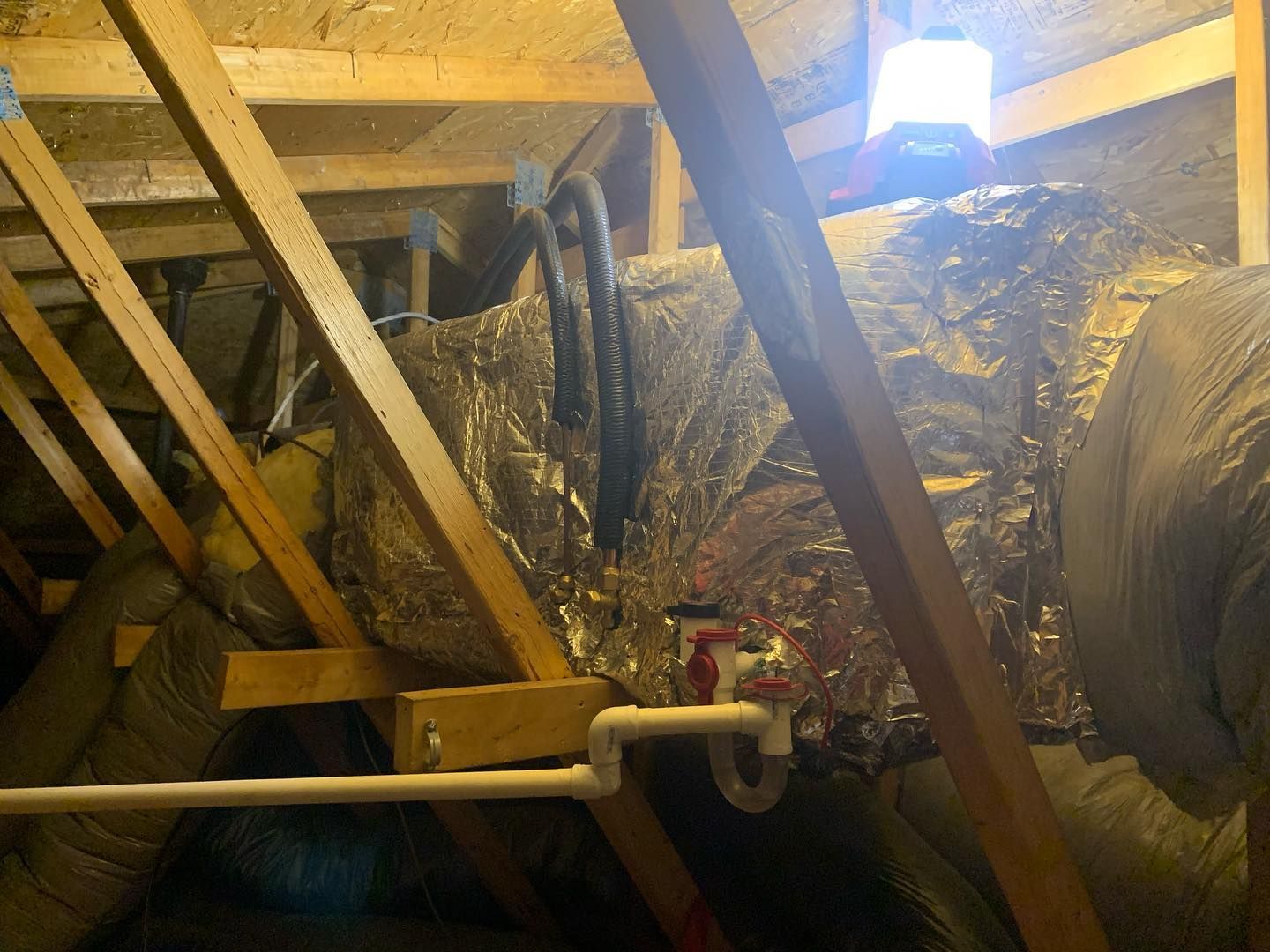 A pipe is hanging from the ceiling of an attic.