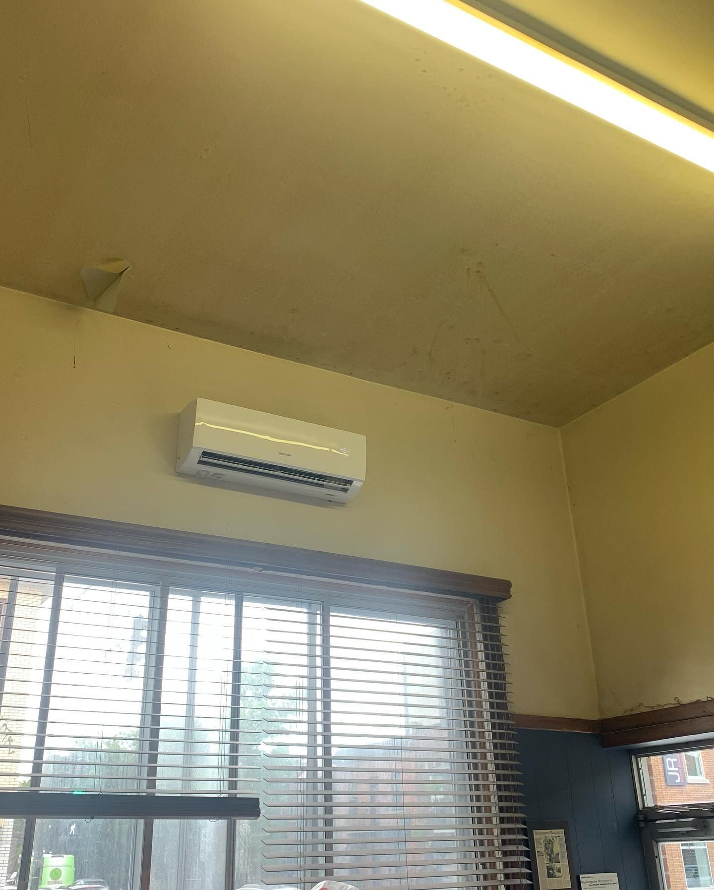 A room with a window and blinds and a ceiling fan