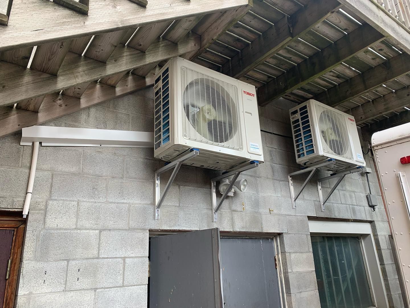 Two air conditioners are mounted on the side of a building.