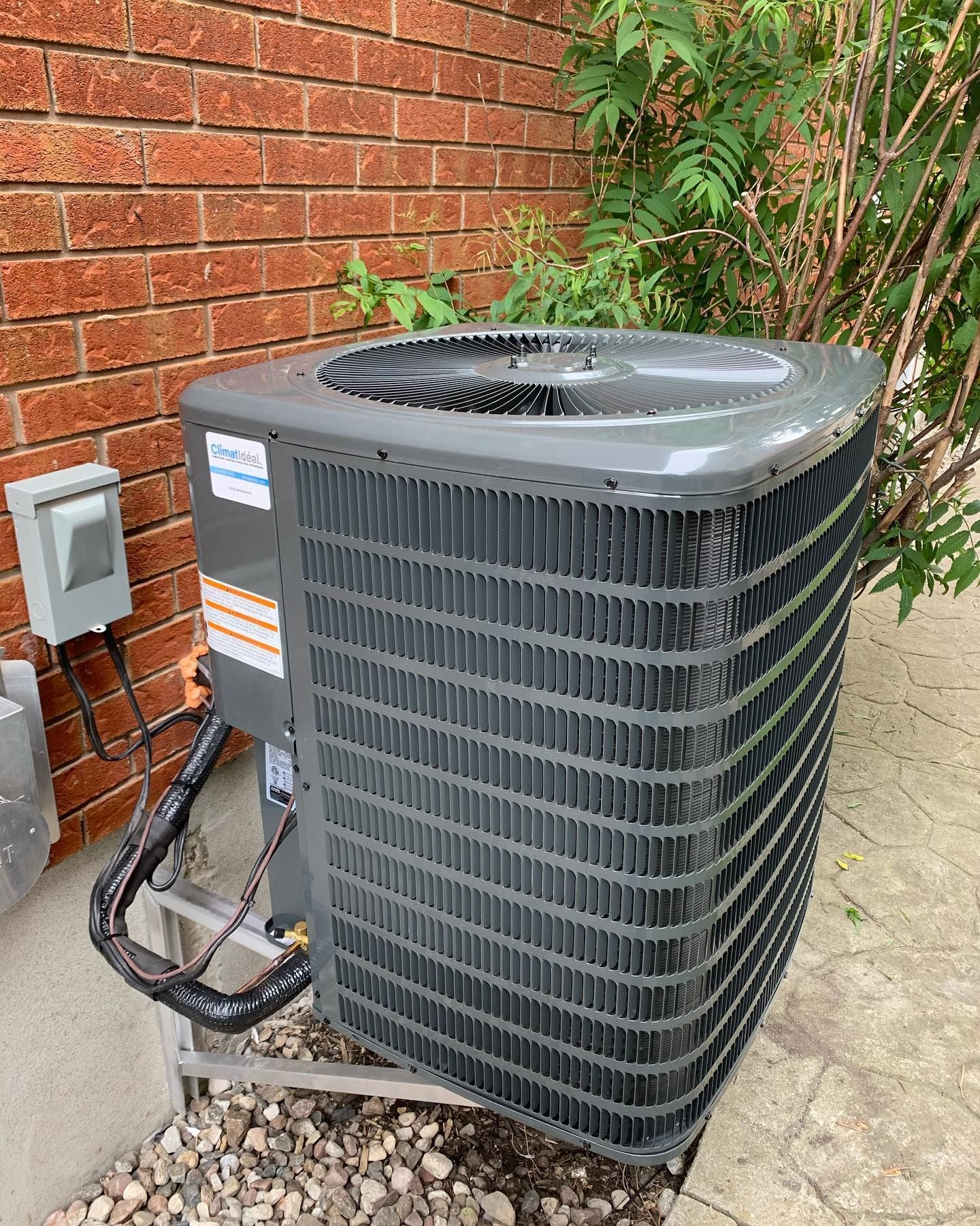 A large air conditioner is sitting on the side of a brick building.