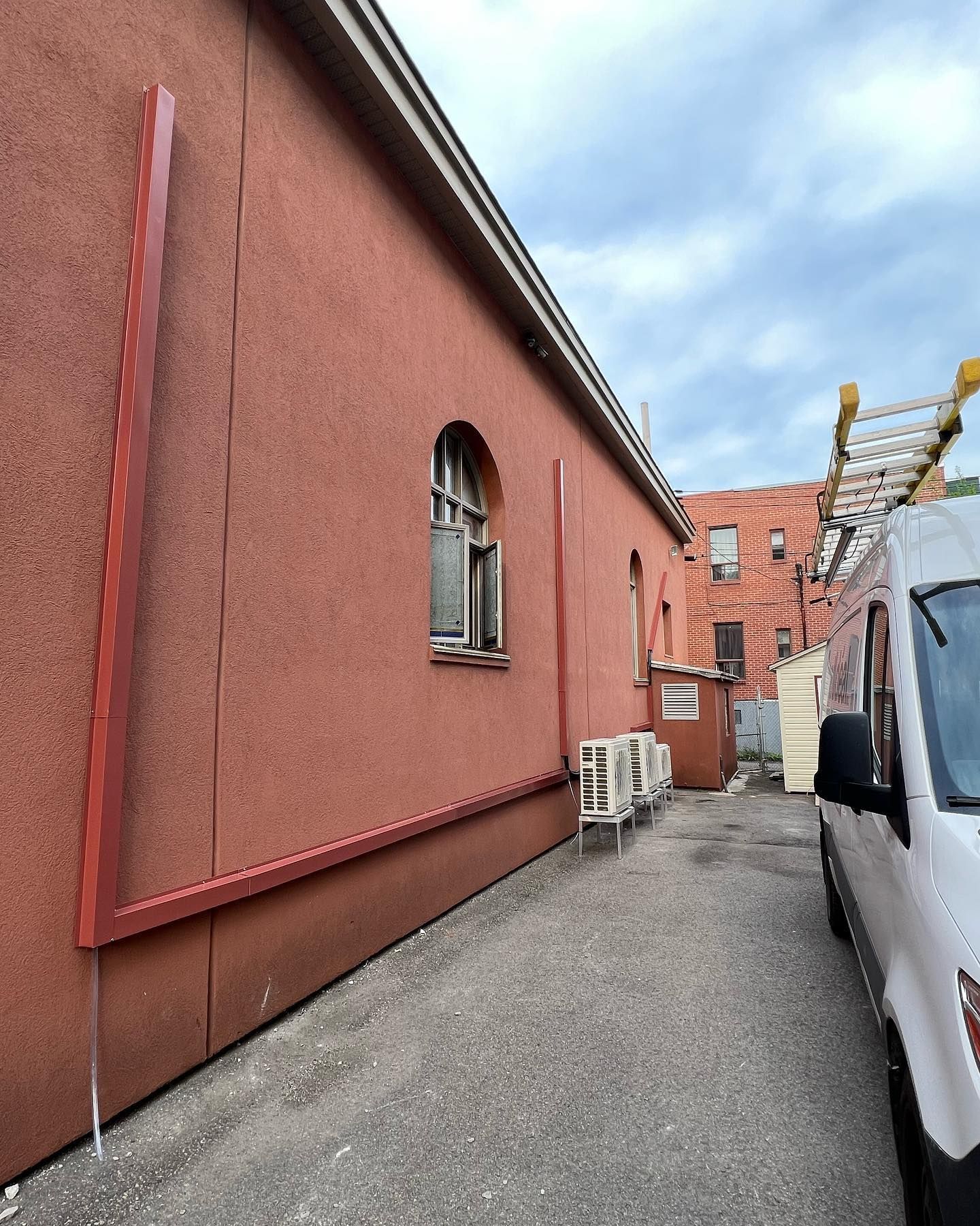A white van is parked in front of a red building