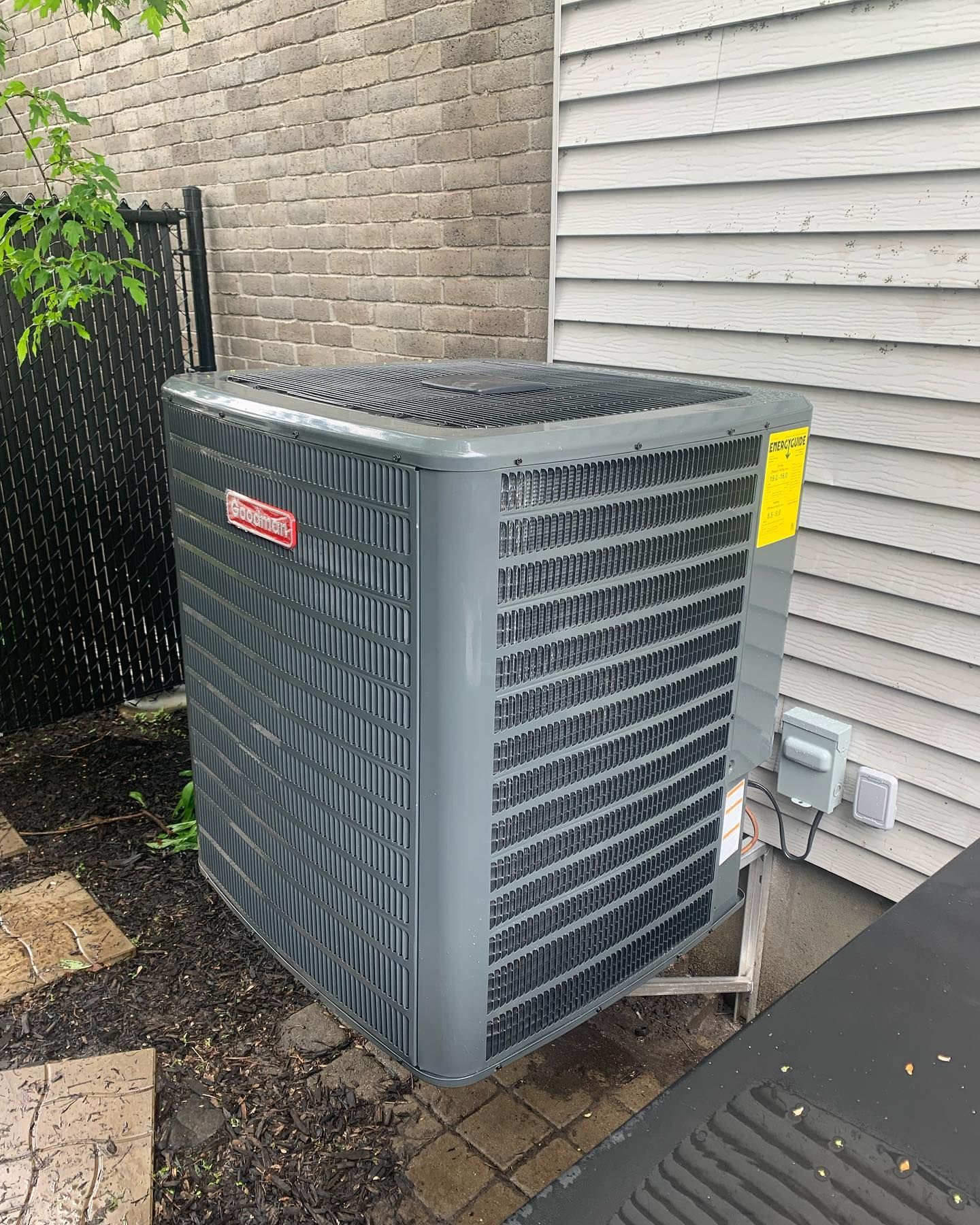 A large air conditioner is sitting on the side of a house.