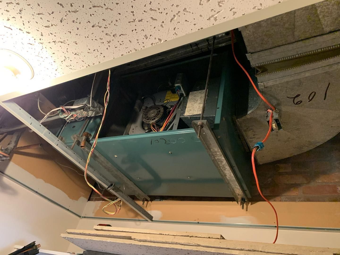 A room with a ceiling fan and a box with wires coming out of it.