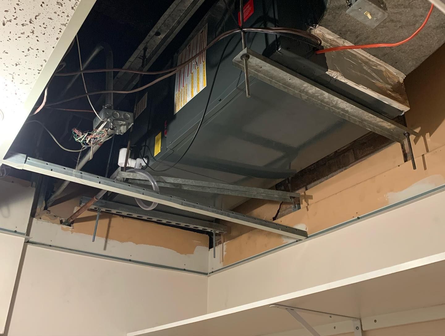 A ceiling with a box hanging from it and wires coming out of it.