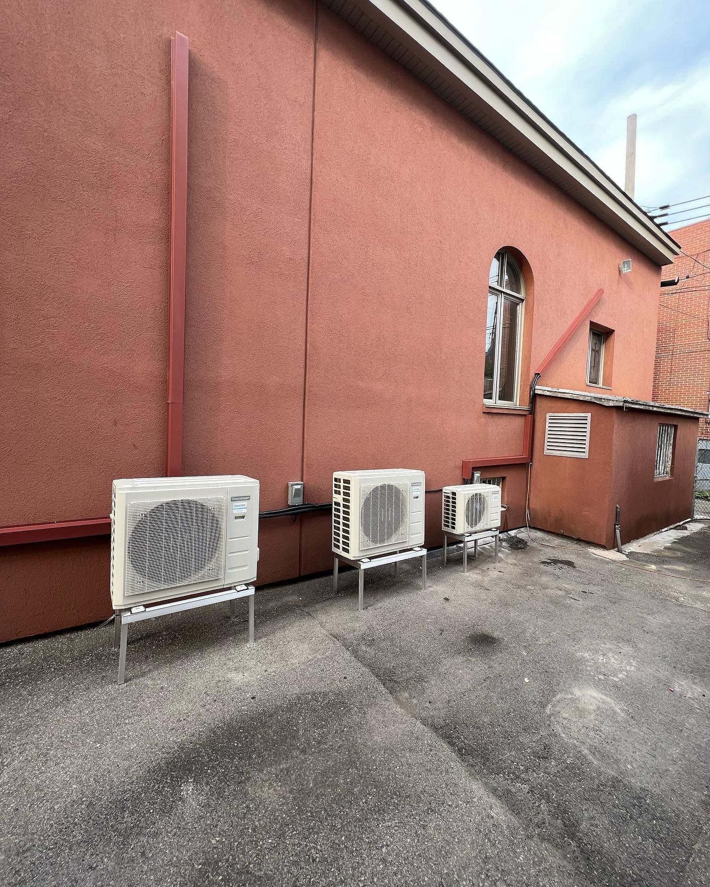 A row of air conditioners are sitting outside of a building.