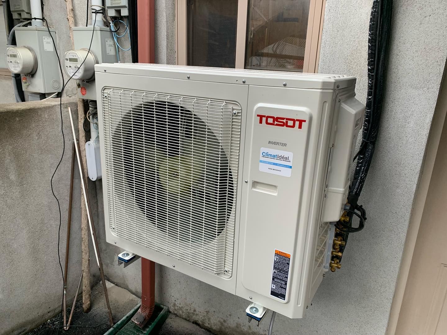 A tosot air conditioner is mounted on the side of a building.