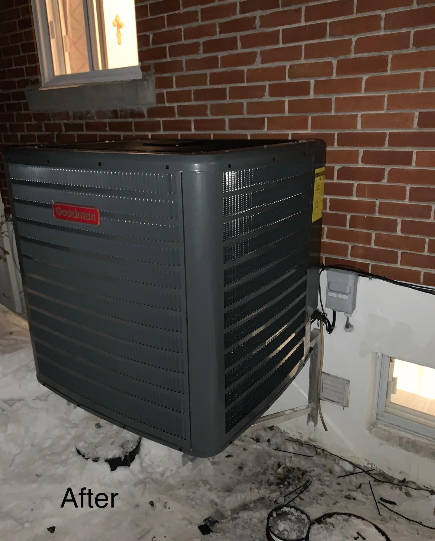 An air conditioner is sitting in front of a brick wall.