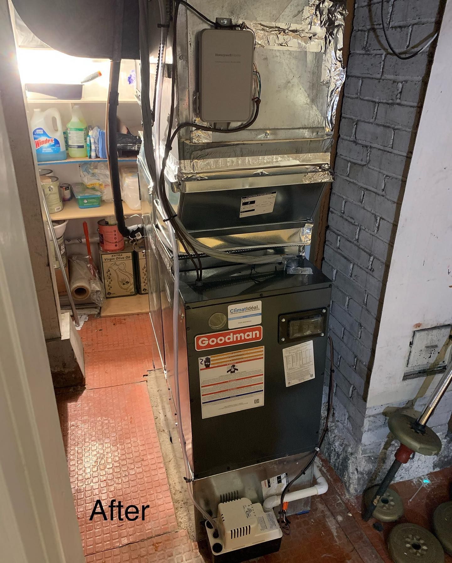 An air conditioner is sitting in a corner of a room next to a brick wall.